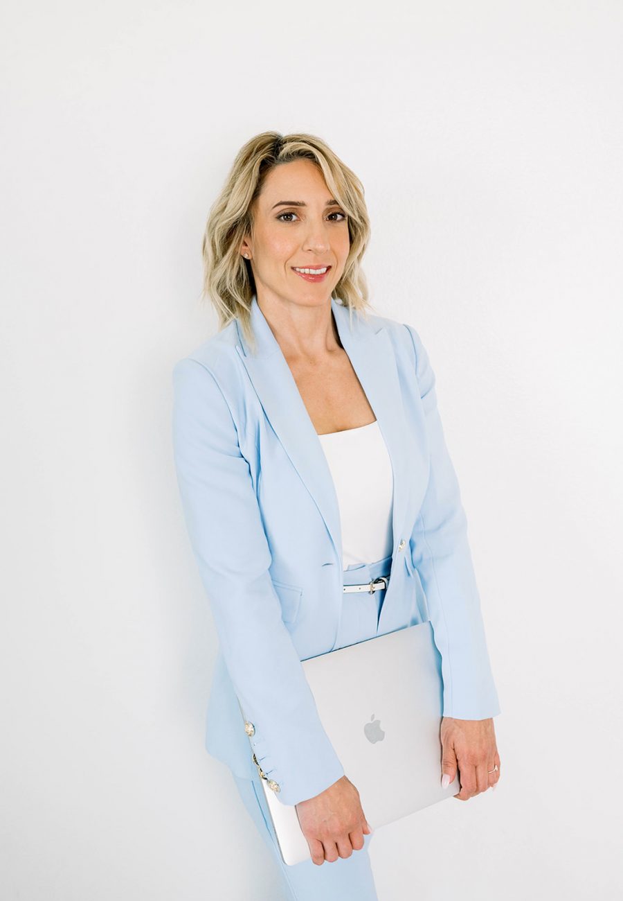Woman in light blue suit holding laptop during branding session.